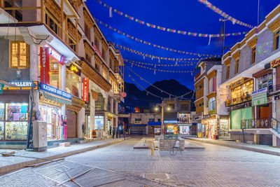 Illuminated street amidst buildings in city at night