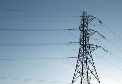 Low angle view of silhouette electricity pylon against clear sky