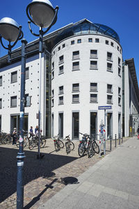 People riding bicycle on street against buildings in city