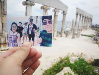 Close-up of hand holding camera against built structure