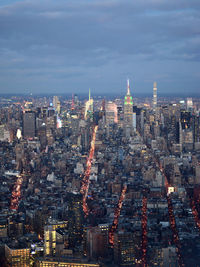 Aerial view of city lit up against sky