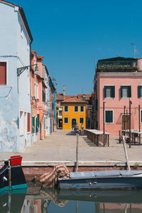 Houses against buildings in city against clear blue sky