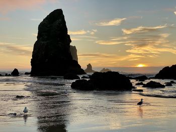 Rocks on sea shore against sky during sunset