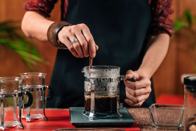 Midsection of woman making coffee in cafe