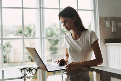 Woman using mobile phone while sitting on table