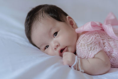 High angle portrait of baby girl lying on bed at home