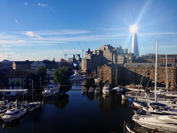 Sailboats moored in harbor against buildings in city