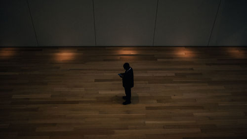 High angle view of man using phone standing in darkroom