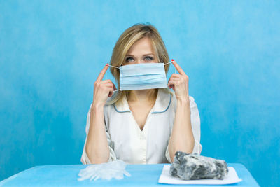 Portrait of a young woman holding blue while sitting on table