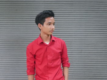 Portrait of young man standing against wall