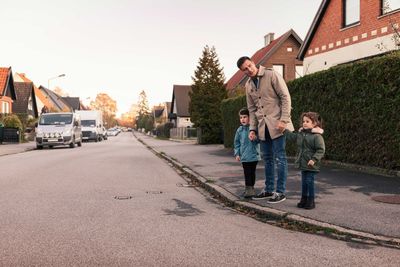 Father standing with children on sidewalk during autumn