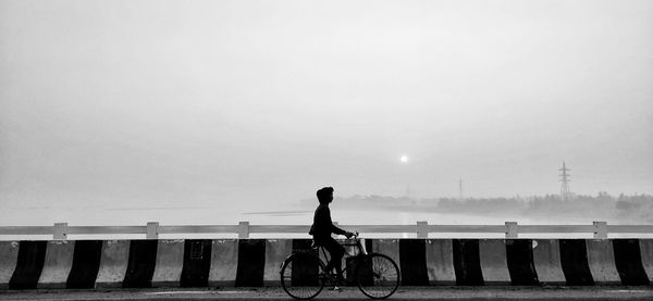 Rear view of man riding bicycle against sky