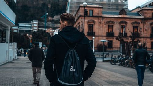 Rear view of man walking on zebra crossing in city