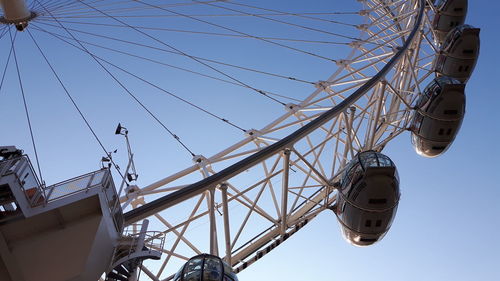 Low angle view of ferris wheel against clear blue sky