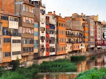 Residential buildings by river against sky