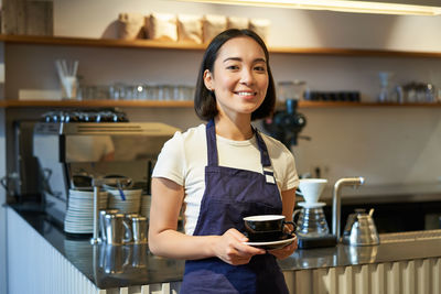 Portrait of young woman standing in cafe