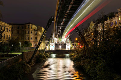 Illuminated bridge over river in city at night