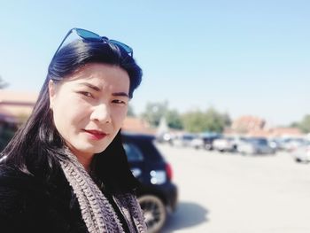 Portrait of young woman in car against sky