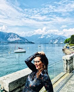 Young woman smiling by sea against sky