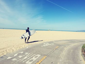 Surfer walking on beach with surfboard