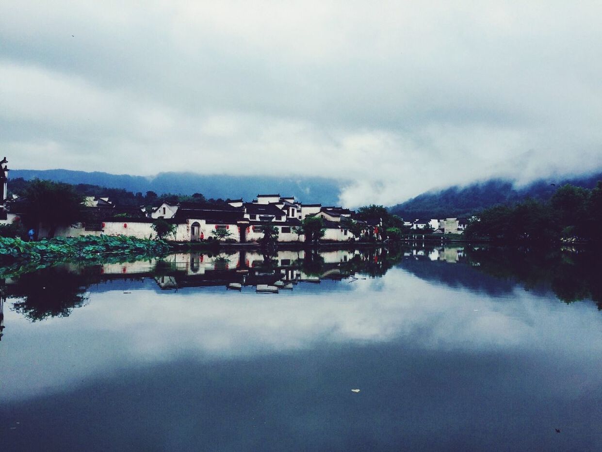 sky, water, architecture, built structure, cloud - sky, building exterior, waterfront, cloudy, reflection, weather, lake, house, overcast, cloud, river, mountain, nature, tranquility, residential structure, tranquil scene