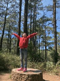 Full length of happy boy standing by tree in forest