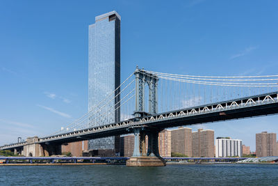 Low angle view of suspension bridge against clear blue sky