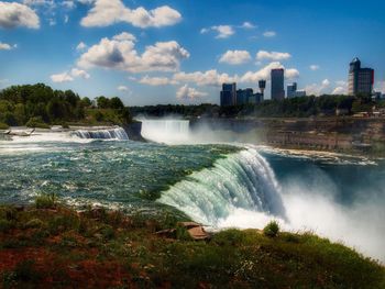 Scenic view of waterfall against sky in city