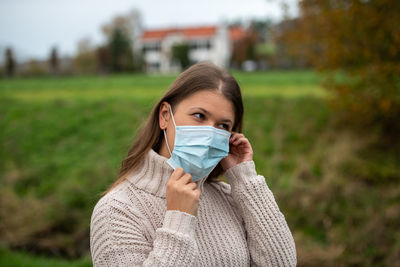 Close-up of young woman wearing mask standing on field