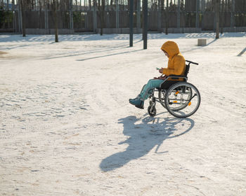 Caucasian woman in a wheelchair uses a smartphone on a walk in the park in winter
