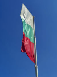 Low angle view of flag against blue sky