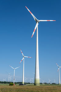 Low angle view of windmill against clear blue sky