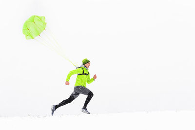 Man with umbrella on snow against sky