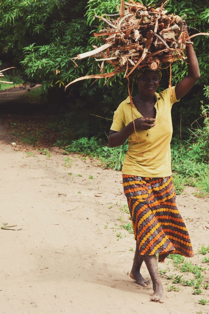 REAR VIEW OF WOMAN STANDING BY TREE ON LAND