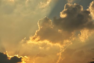 Low angle view of sunlight streaming through clouds