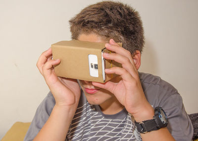 Close-up of boy looking in smart phone through cardboard virtual reality simulator