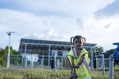 Girl opening a water valve with solar panels in the background. person