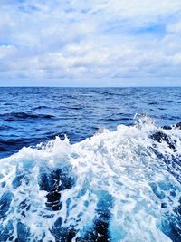 Scenic view of sea waves against cloudy sky