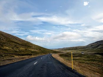 Empty road along landscape against sky