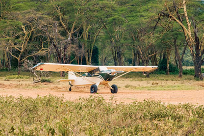 A light aircraft on a dirt airstrip amidst acacia trees at lake nakuru national park in kenya