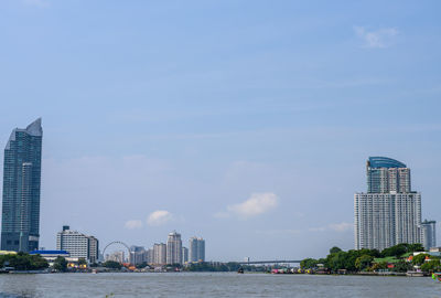Sea and modern buildings in city against sky