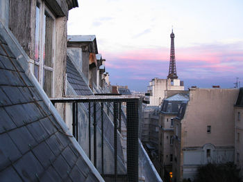 Distant view of eiffel tower amidst buildings in city at dusk