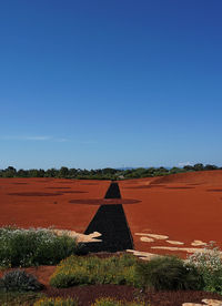 Built structure on field against clear blue sky