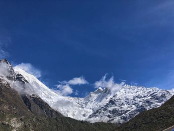 Scenic view of snowcapped mountains against blue sky