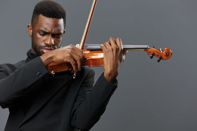 Midsection of man playing violin against white background