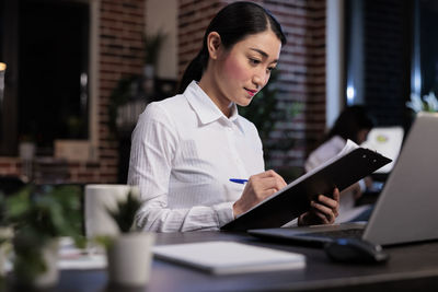 Businesswoman writing while working at office