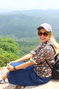 Portrait of mid adult woman wearing sunglasses sitting on mountain