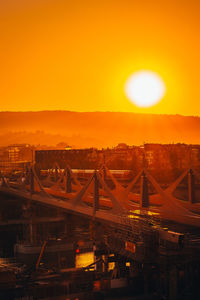 Bridge in city against orange sky