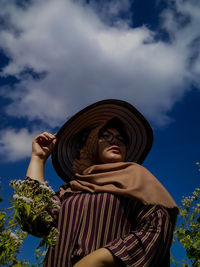 Low angle view of woman wearing hat against sky