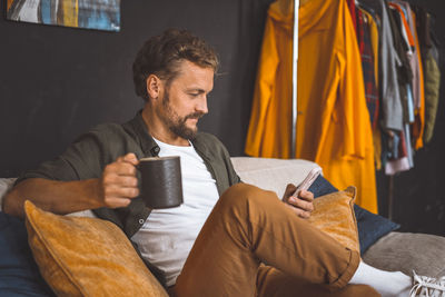 Young man using phone while sitting at home